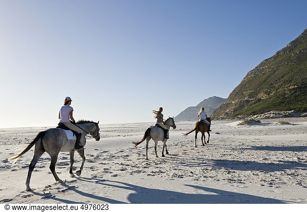 3 Personen auf Pferden am Strand