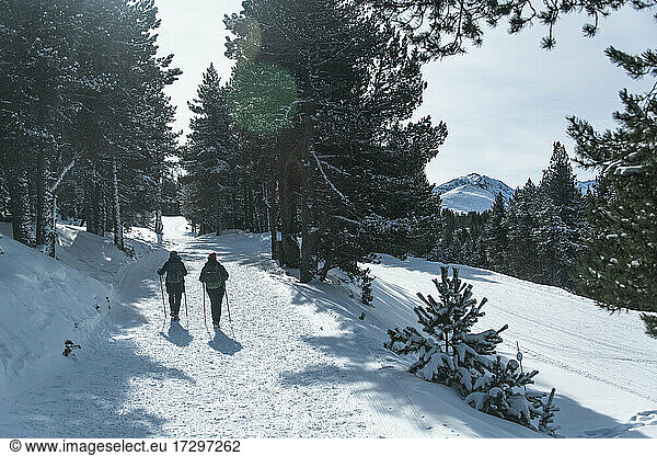2 persons are hiking in the snow towards a mountain peak