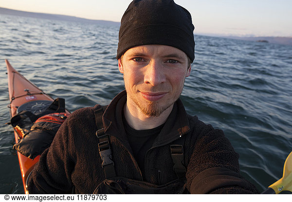 'Portrait of a young man in a kayak on the water at sunset  Kachemak Bay State Park; Alaska  United States of America'