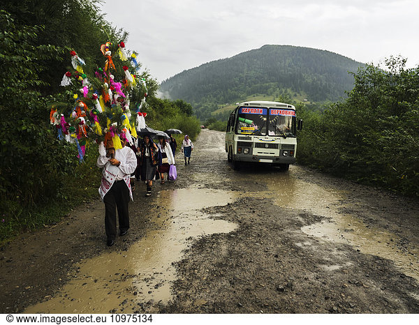 'Relatives and friends escort the bride to church on the road in the rain; Kryvorivnia  Verkhovyna district  Ivano-Frankivsk region  Ukraine.'