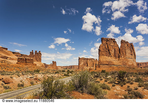 'Rugged rock formations and shrubs in the desert  with a road passing through; Arizona  United States of America'