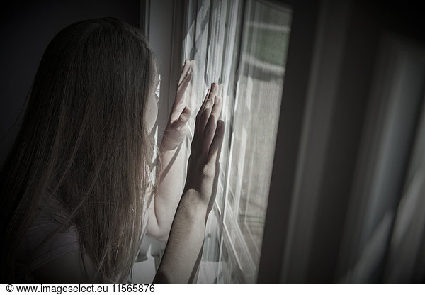 'Teenage girl looking out a window; Connecticut  United States of America'