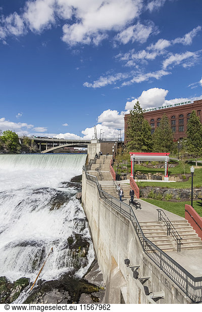 'The Monroe Street Dam and spillway  pedestrian walkway along the river in the foreground  downtown Spokane; Spokane  Washington  United States of America'
