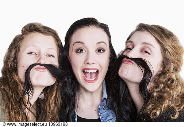 'Three young women in a humorous pose using long hair for a moustache; Alberta  Canada'