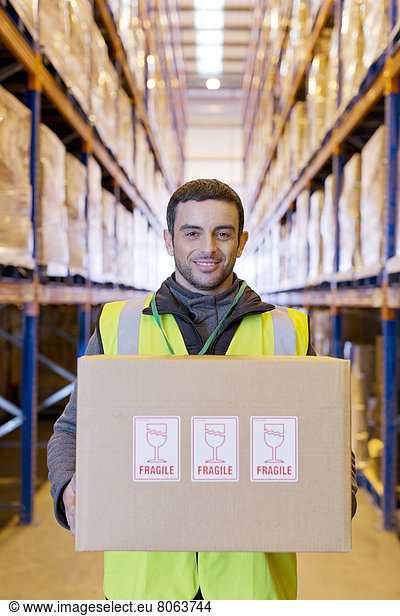 'Worker carrying ''fragile'' box in warehouse'