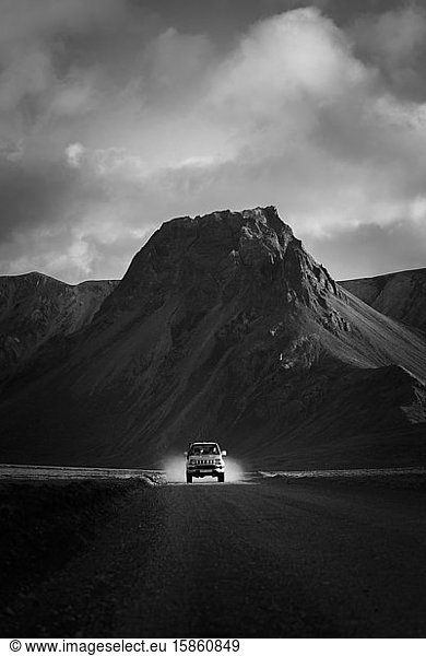 4x4-Fahrt im Staub zur Kamera im Sonnenlicht vor dem Berg