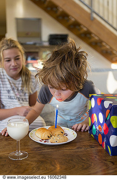 5 year old boy blowing out candle on croissant