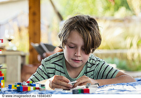 7 year old boy playing with building blocks on a terrace