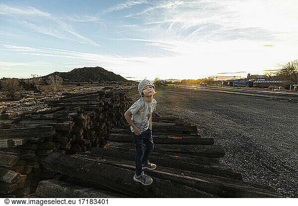 7 year old boy standing alone on railroad ties at sunset