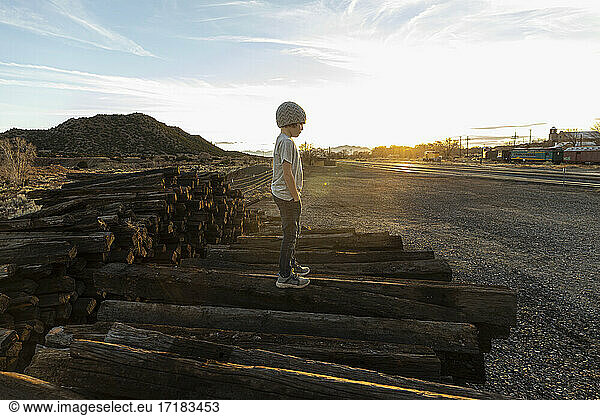7 year old boy standing alone on railroad ties at sunset