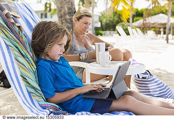 5 year old boy using laptop at the beach