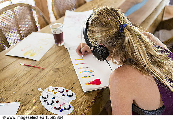 13 year old girl wearing headphones  doing watercolor sketch