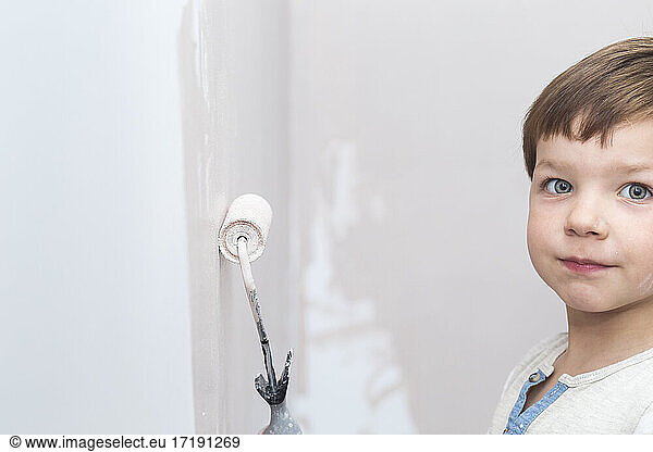 3 years cute little boy with paint roller in hand