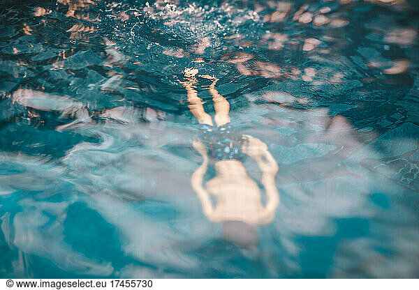 8 years old faceless boy swimming in a pool