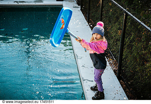 5 years old girl cleaning the swimming pool during fall