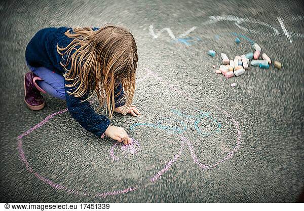 5 years old girl doing some chalks on her driveway