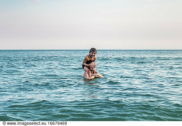 5 years old kid on top of his mother's shoulders  into the ocean