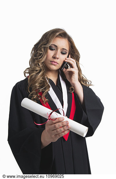 'Young graduating woman holding her diploma and talking on her smart phone; Edmonton  Alberta  Canada'