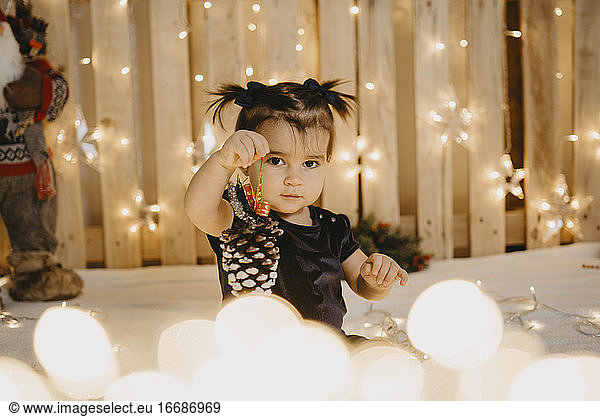A baby girl with pigtails shows a Christmas pineapple