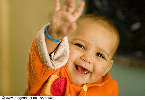 A baby with kohl on its eyes and a blue bracelet waves at visitors to a kindergarten in Kabul  Afghanistan.
