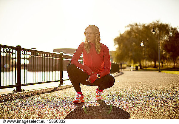 A backlit portrait of a female runner at rest.