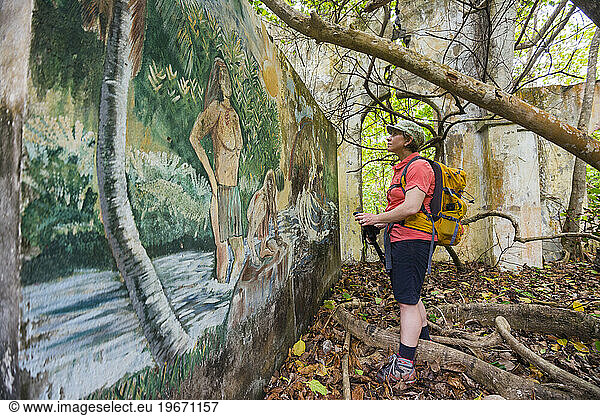 A backpacker looks at a mural in the ruins of an old church in the Kalinago territory on Segment 6 of the Waitukubuli National Trail on the Caribbean island of Dominica. The church