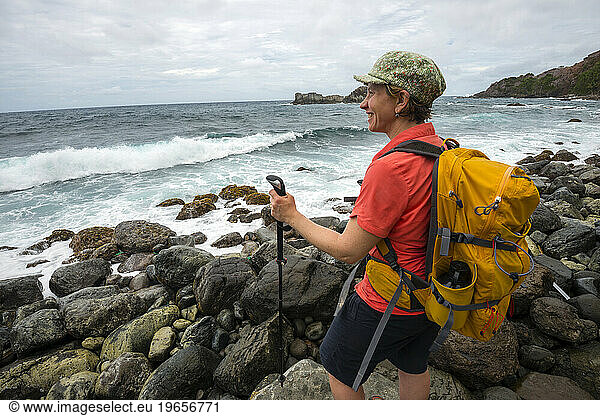 A backpacker looks out over the Atlantic Ocean while hiking Segment 6 of the Waitukubuli National Trail on the Caribbean island of Dominica.