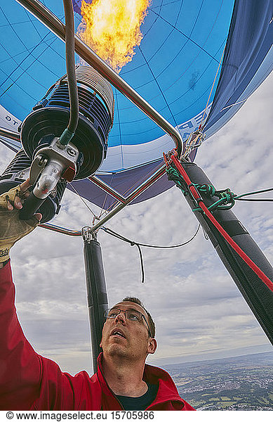 A balloon pilot adjusting the burning gas jets that heat air inside the balloon  during the Bristol International Balloon Fiesta  England  United Kingdom  Europe