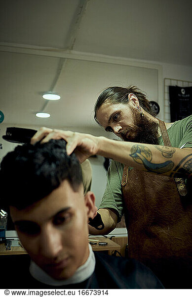 A barber concentrating on cutting a customer's hair