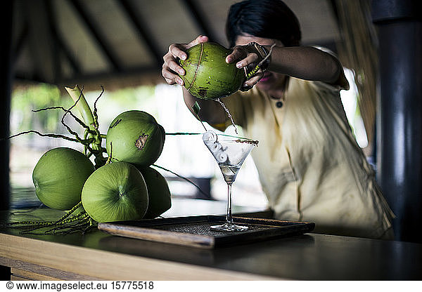 A bartender mixing a martini (Praow-Tini) out of a coconut shaker.