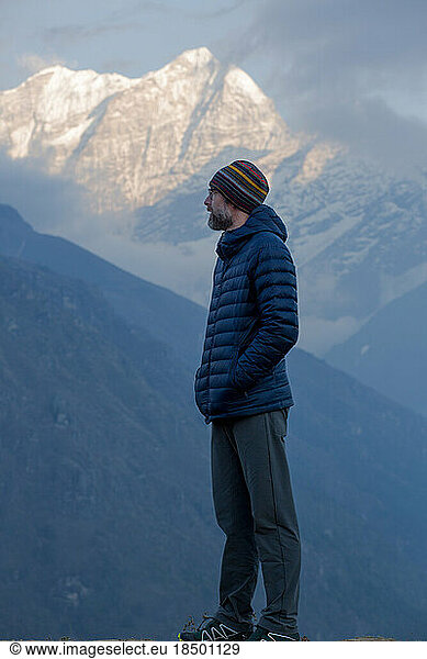 A bearded man overlooks the Himalayan peaks at dusk.