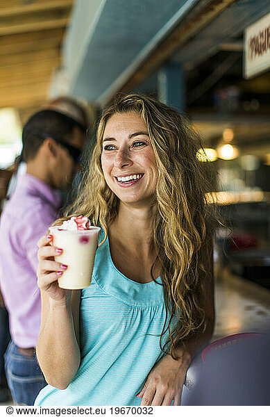 A beautiful woman enjoys a pina colada at a dive bar in Puerto Rico.