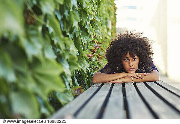 A beautiful woman lying in a park.She has beautiful afro hair.