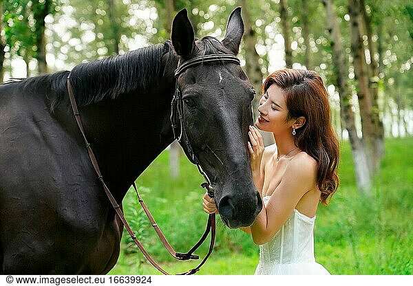 A beautiful young woman intimacy stroked the horse