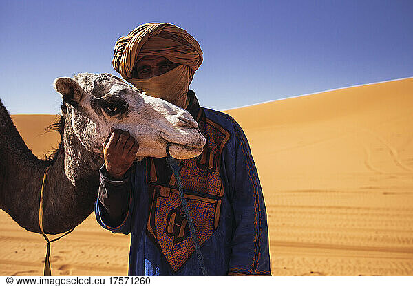 A Bereber guide hugging his camel in Merzouga desert  Morocco.