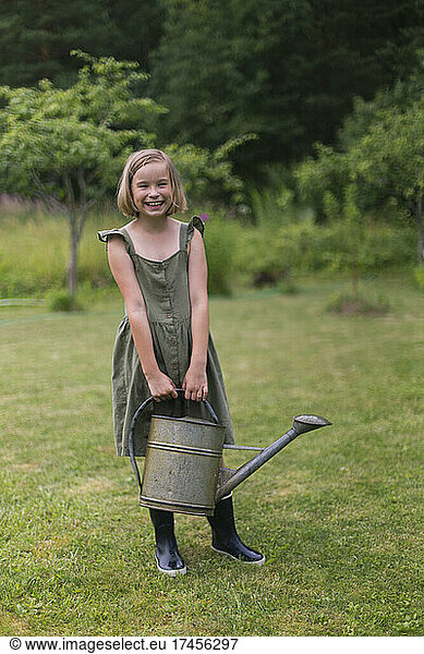 A blonde girl is holding a garden tool