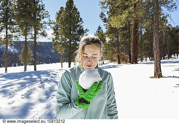 A blonde teenage girl holding a snowball