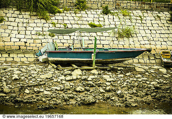 A boat sitting on the banks of a canal.