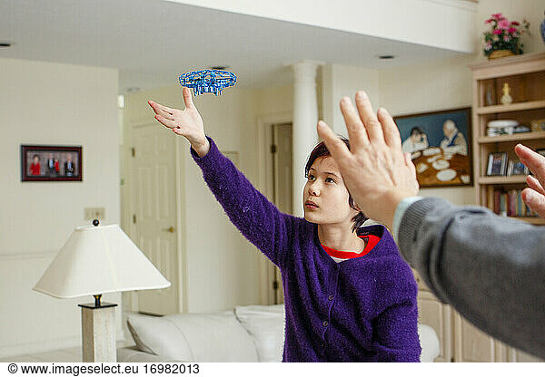 A boy and father reach out towards hovering flying toy in living room