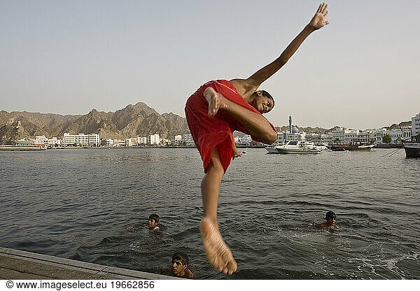 A boy dives into the water of Sultan Qaboos Port in Muscat  Oman.