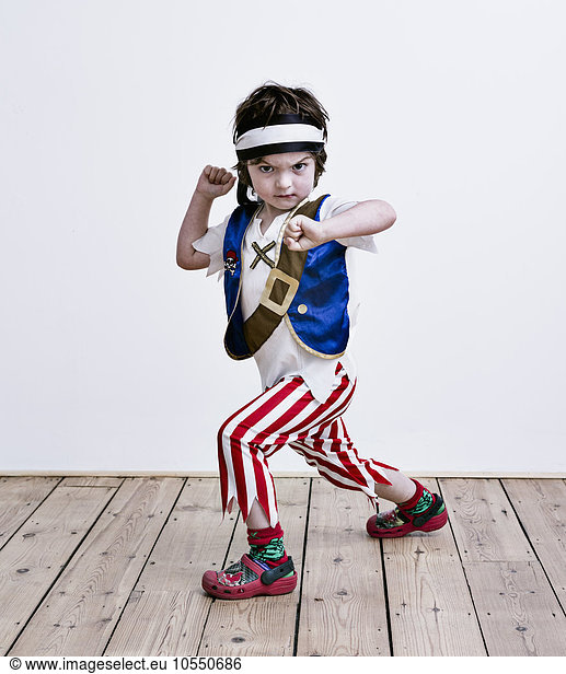 A boy in fancy dress costume  striped trousers and a belt  dressed as a pirate.