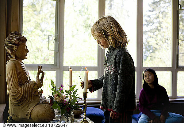 A boy lights incense at an alter during a Buddhist family retreat on Vashon Island  Washington.