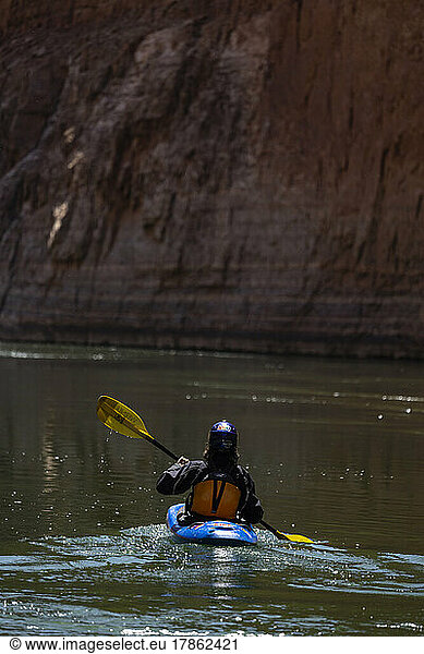 A boy paddling a kayak on the Colorado river in the Grand Canyon