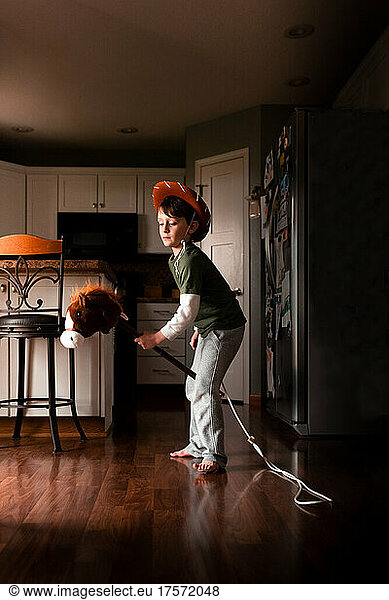 a boy playing cowboy on his toy horse at home