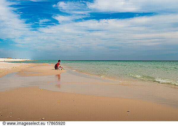 a boy playing in the sand on the beach at gulf islands in Florida