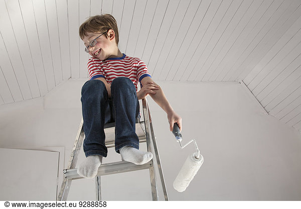 A boy seated on a stepladder.