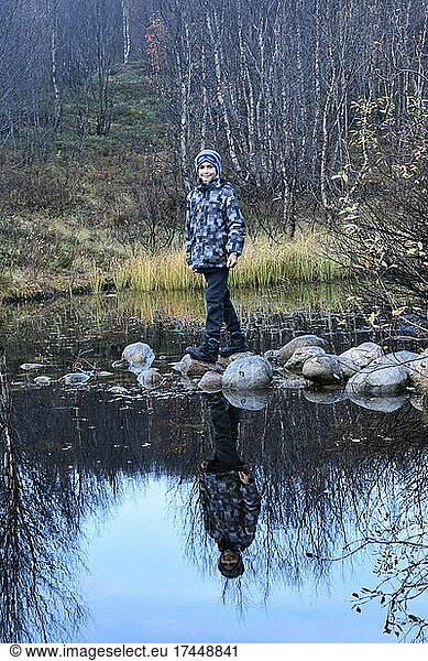 a boy stands on a rock