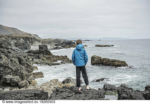 A boy stands on the coastal cliffs of Iceland's north coast.