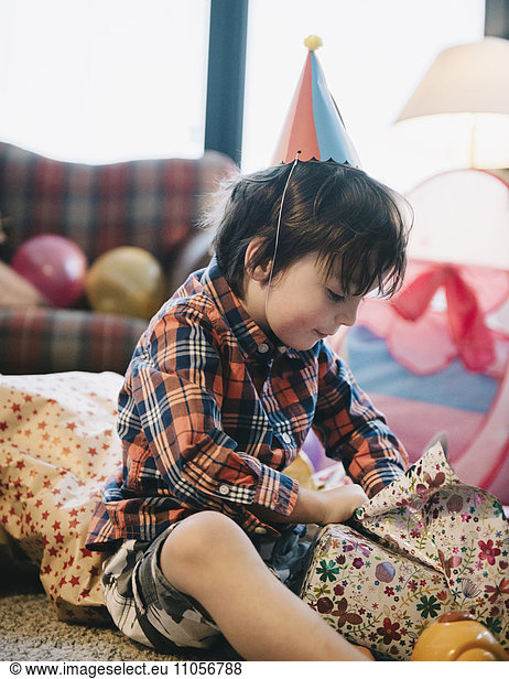 A boy unwrapping his presents at his birthday party.