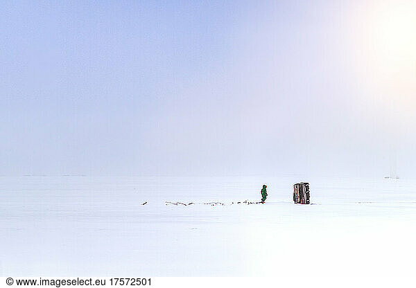 A boy walking through the snow on a wind farm in Iowa